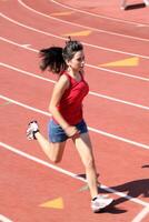 joven latina niña corriendo en pista pantalones cortos rojo parte superior foto