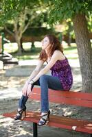 Young caucasian teen girl sitting on park bench photo