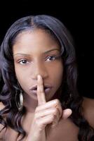 joven africano americano mujer con dedo a labios foto