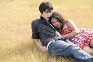 Young teen couple reclining in yellow grass photo