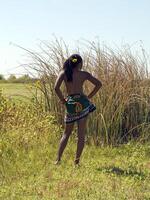 Young black woman in field bare top from back photo