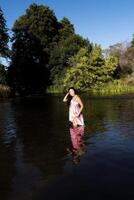 sonriente joven japonés americano mujer en pie en río foto