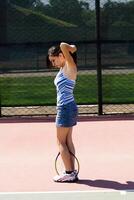 Young Hispanic Teen Woman On Tennis Court Fixing Her Hair photo