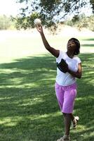 joven africano americano mujer lanzamiento béisbol parque foto