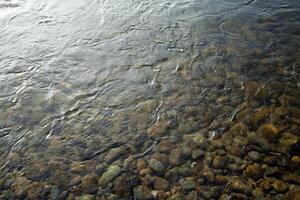 guijarros y rocas debajo corriendo río ondas foto