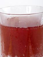 Red carbonated drink in frosted crystal glass closeup photo