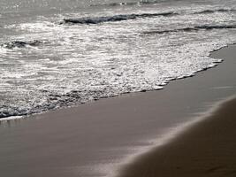 amable ola de blanco espuma en el playa foto