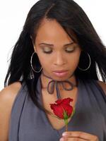joven negro mujer mirando abajo a rojo Rosa foto