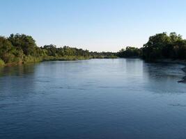 River With Green Trees On Both Shores And Blue Sky photo