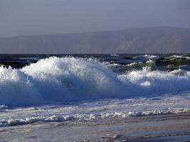 wave crashing on wild beach with foam photo