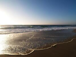 Ocean Waves Reaching Up On Sand Beach Blue Sky photo