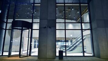 Night view on the ground floor of modern office building with big glass windows and entrance. Street reflection. photo