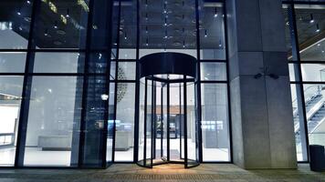 Night view on the ground floor of modern office building with big glass windows and entrance. Street reflection. photo