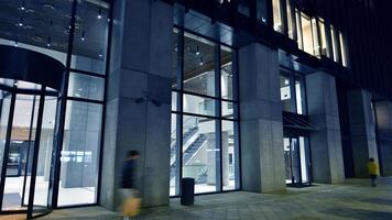 Night view on the ground floor of modern office building with big glass windows and entrance. Street reflection. photo