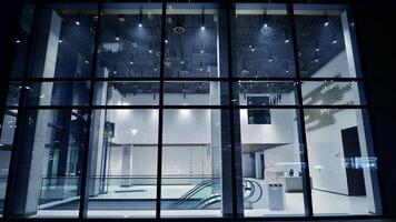 Night view on the ground floor of modern office building with big glass windows and entrance. Street reflection. photo