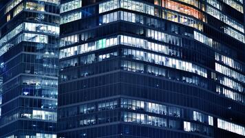 Office buildings by night. Night architectural, buildings with glass facade. Modern buildings in business district. Concept of economics, financial. photo