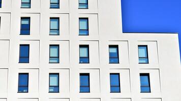 View of a white modern apartment building. Perfect symmetry with blue sky. Geometric architecture detail modern concrete structure building. Abstract concrete architecture. photo