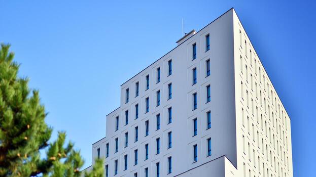 View of a white modern apartment building. Perfect symmetry with blue sky. Geometric architecture detail modern concrete structure building. Abstract concrete architecture. photo