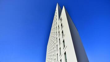 View of a white modern apartment building. Perfect symmetry with blue sky. Geometric architecture detail modern concrete structure building. Abstract concrete architecture. photo