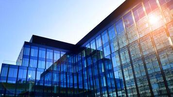 Modern office building with glass facade. Transparent glass wall of office building. Reflection of the blue sky on the facade of the building. photo