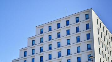 View of a white modern apartment building. Perfect symmetry with blue sky. Geometric architecture detail modern concrete structure building. Abstract concrete architecture. photo
