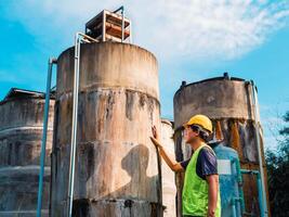 asiático hombre ingeniero controlador el calidad de agua lugares operando industrial agua purificación o filtración equipo antiguo cemento tanques para acuerdo agua en agua fábrica foto