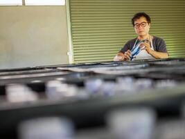 Young Asian man worker wear working in checking bottled drinking water in drink water factory before shipment.drinking water business. photo