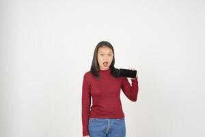 joven asiático mujer en rojo camiseta Guau conmocionado y demostración teléfono inteligente blanco pantalla aislado en blanco antecedentes foto