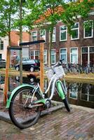 Bicycle parked near the canal in Delft street with old houses. Delft, Netherlands photo