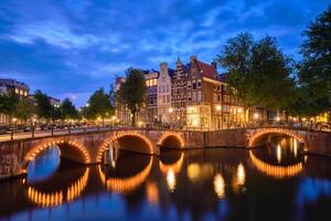 Amsterdam canal, puente y medieval casas en el noche foto