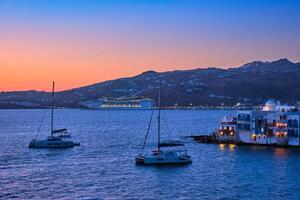 Sunset in Mykonos, Greece, with cruise ship and yachts in the harbor photo