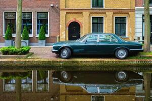 Old car on canal embankment in street of Delft. Delft, Netherlands photo