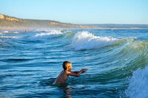 Boy having fun jumping in ocean sea waves photo