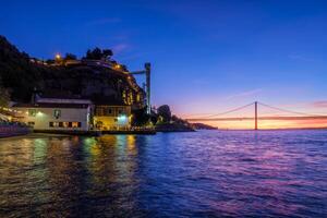 View of 25 de Abril Bridge over Tagus river on sunset. Lisbon, Portugal photo