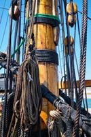 Mast of old wooden Age of sail sailing ship with ropes cordage. and shroud photo