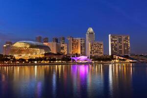 Singapore skyline skyscrapers over Marina Bay illuminated in evening photo