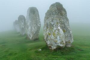 AI generated row of ancient megalithic stones on a foggy morning in a meadow photo