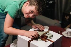 Excited boy unwrapping large birthday cake box for surprise gift photo