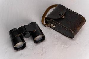 Vintage theatrical binoculars in leather case on white background with copy space photo