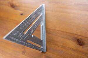 Swanson's aluminum roofing square on wooden table for construction and carpentry projects photo