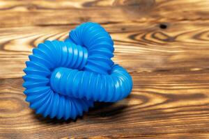 blue children's corrugated pipe toy. Pop Tubes, pipe accordion, antistress. on Wooden Surface photo