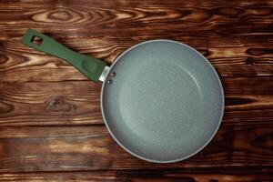 Frying Pan With Green Handle on Wooden Table photo