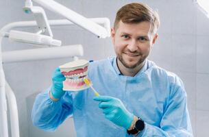 A model of a human jaw with teeth and a toothbrush in the dentist's hand photo