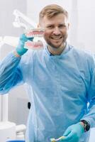 A model of a human jaw with teeth and a toothbrush in the dentist's hand photo