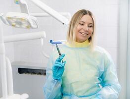 The dentist holds an injection syringe for the patient in the office photo