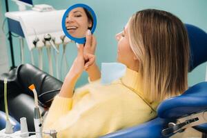 The girl smiles and looks in the mirror in dentistry photo