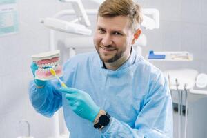 A model of a human jaw with teeth and a toothbrush in the dentist's hand photo