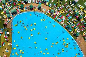 parte superior ver de personas relajante en el piscina en amarillo inflable círculos y Dom camas en el playa foto