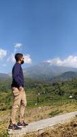 Mojokerto, Indonesia, 20 May 2023 - A man enjoys the view of the mountain landscape and rice fields photo