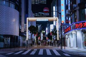 un noche paisaje urbano de el multitud a el neón pueblo en Shinjuku tokio foto